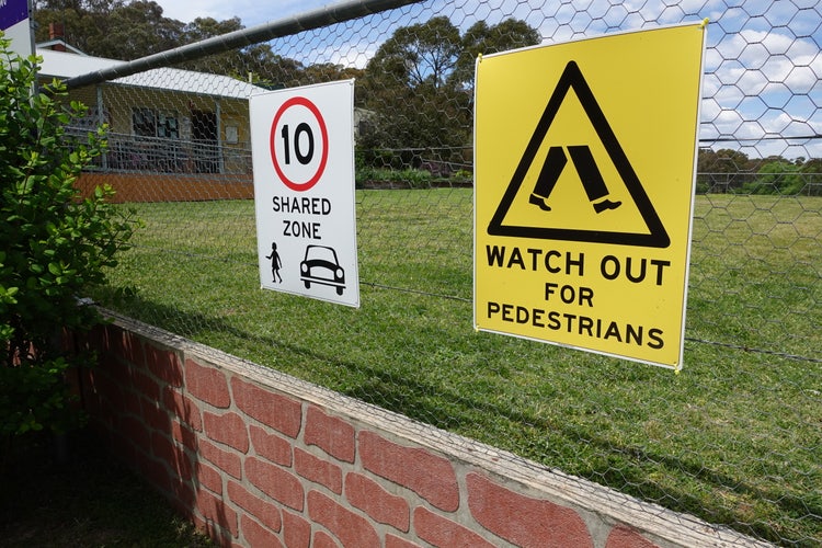 Two signs on mesh wire fence. White sign with 10 in red circle,