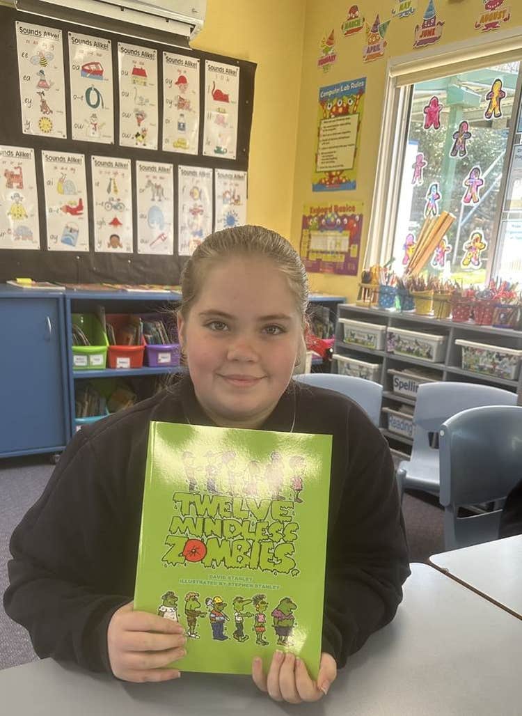 A smiling student holding a book in our main classroom
