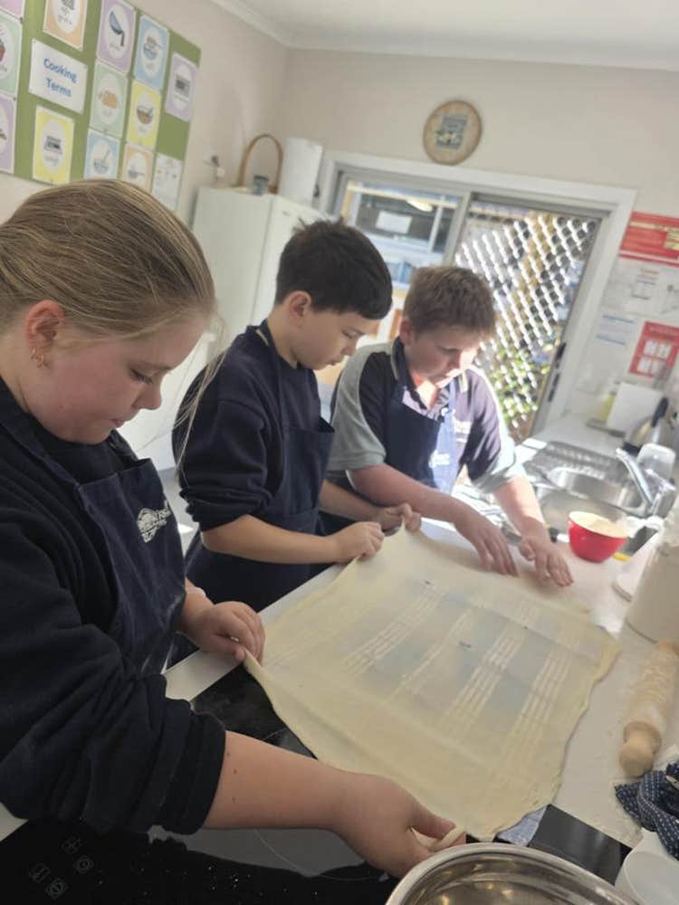 3 students preparing food in our kitchen classroom