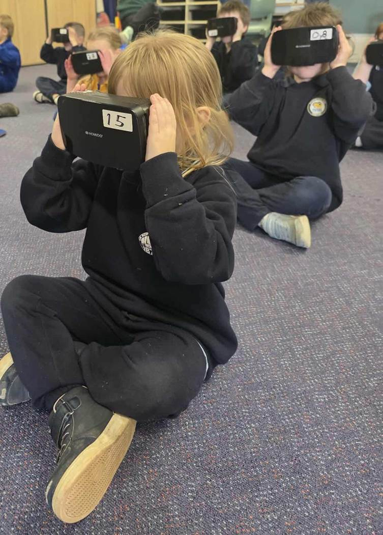 A group of children sitting on the floor using 3D goggles