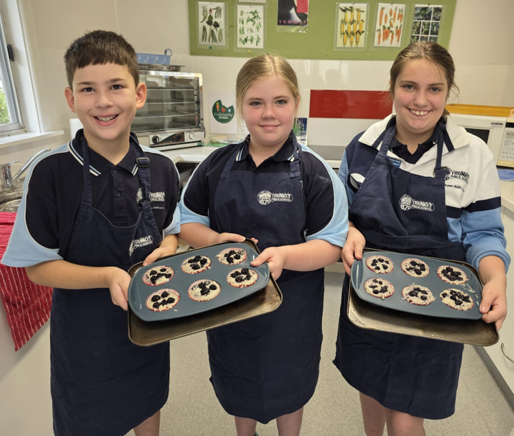 3 students holding their blueberry muffins before they go in the oven.