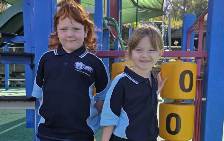 2 kindergarten students standing at the play equipment