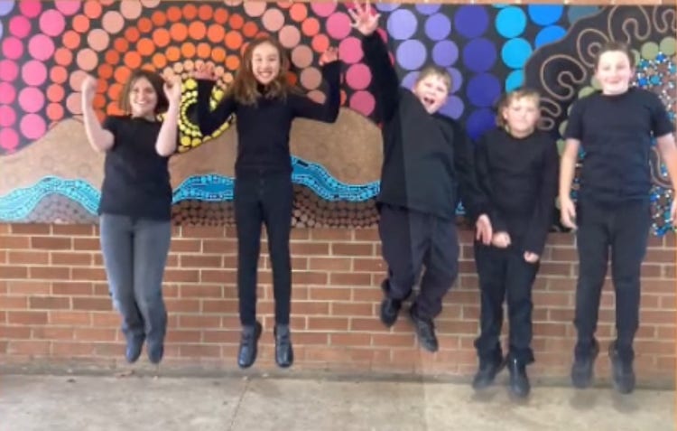 5 students from the Tournament of Minds team dressed in black in front of an Aboriginal artwork