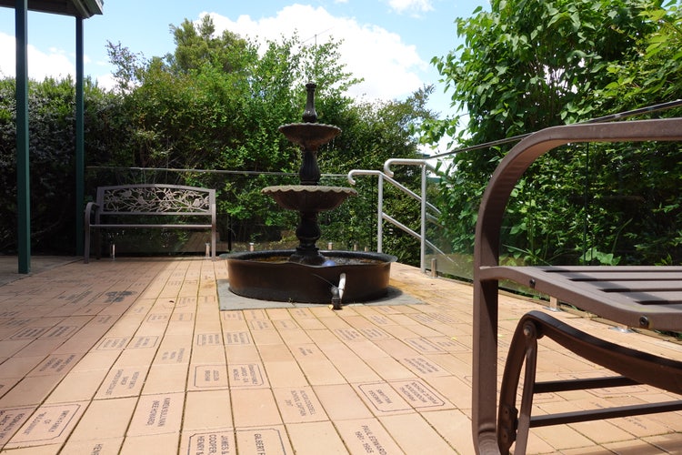 Our sesquicentenary garden, paved with student and staff names on pavers, a fountain in the centre, 2 garden seats and plants all around.