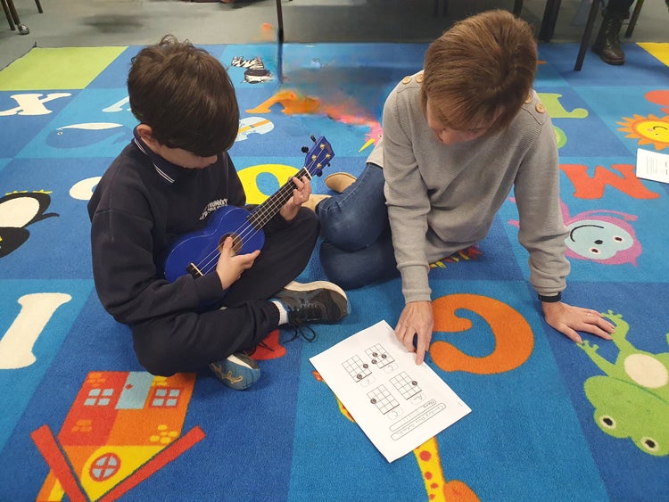 SLSO, Karen Brown, assisting a Trunkey Public School student learning ukulele
