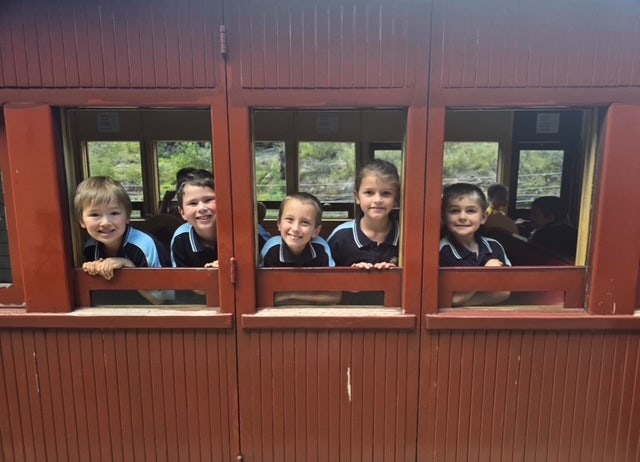 5 students looking out the windows of an old train on the Zig Zag Railway